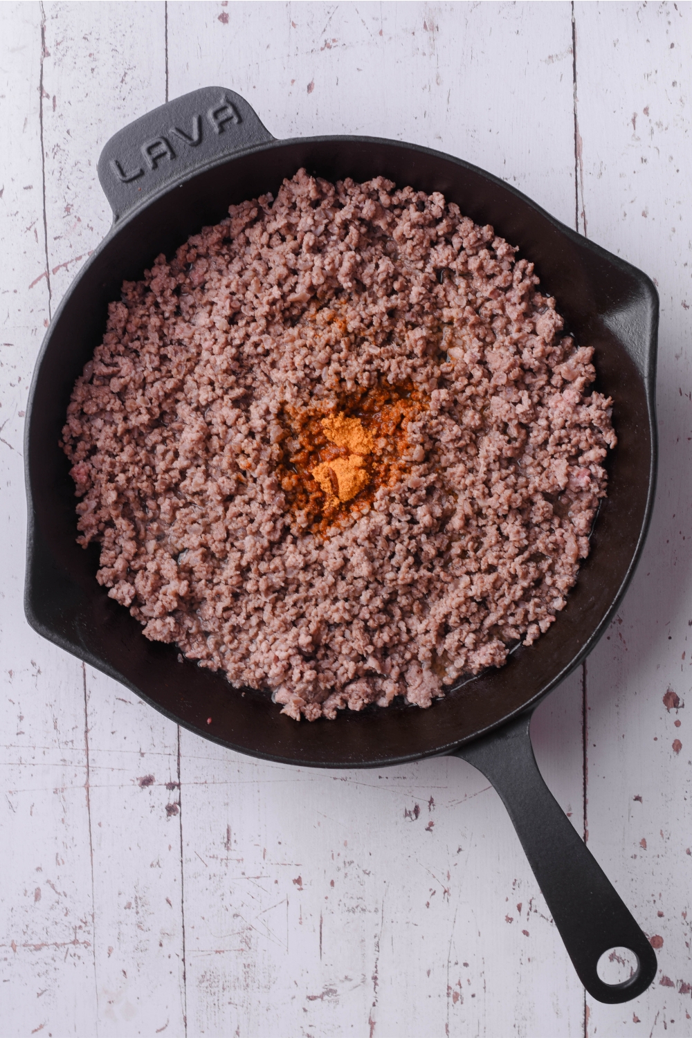 Cooked ground beef with taco seasoning in the middle in a skillet.