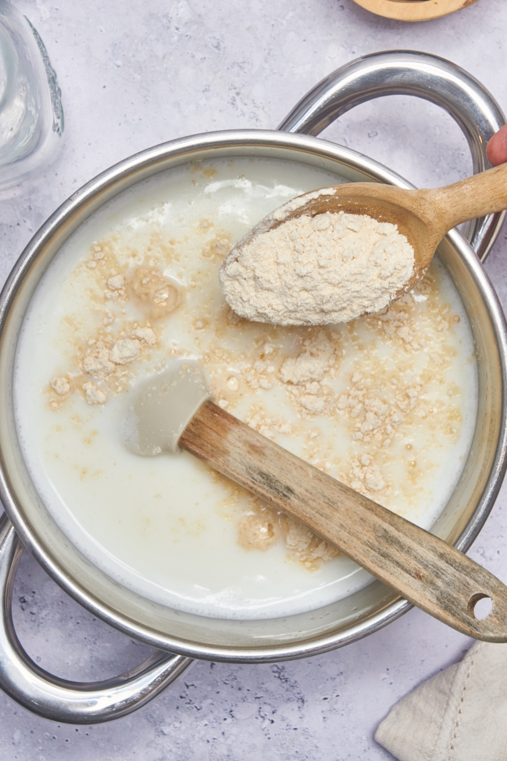 A sauce pot with hot milk, a wooden spoon is adding the cream of wheat to it.