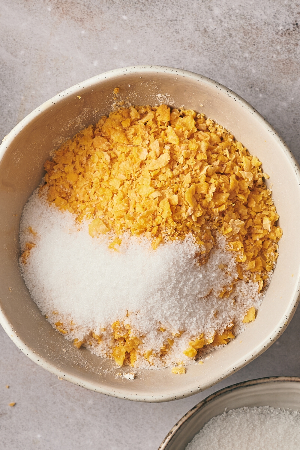A mixing bowl with sugar and cornflakes.