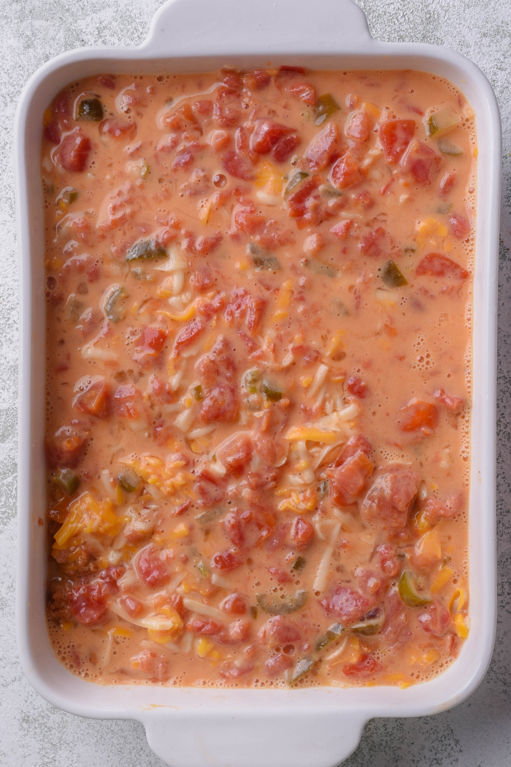 A baking dish with unbaked Mexican casserole in it.