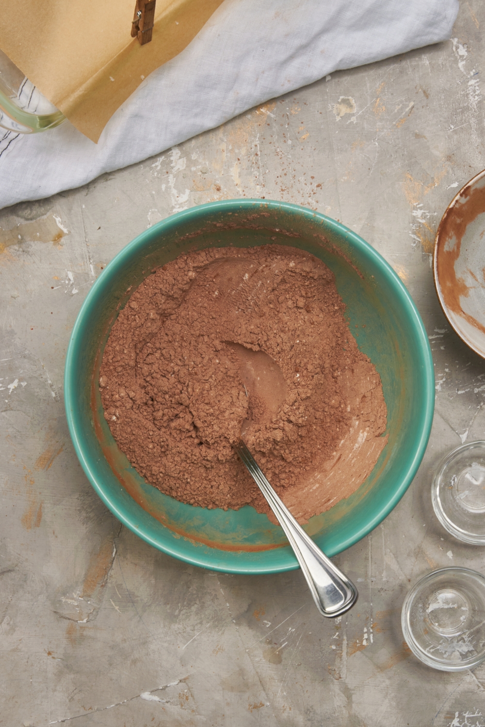 Coco powder mixed with flour in a bowl with a spoon in it.