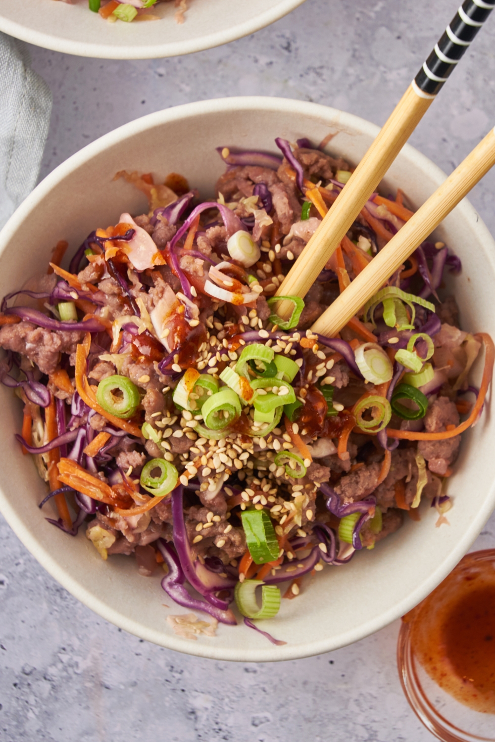 A bowl with crack slaw and a set of chop sticks in it.