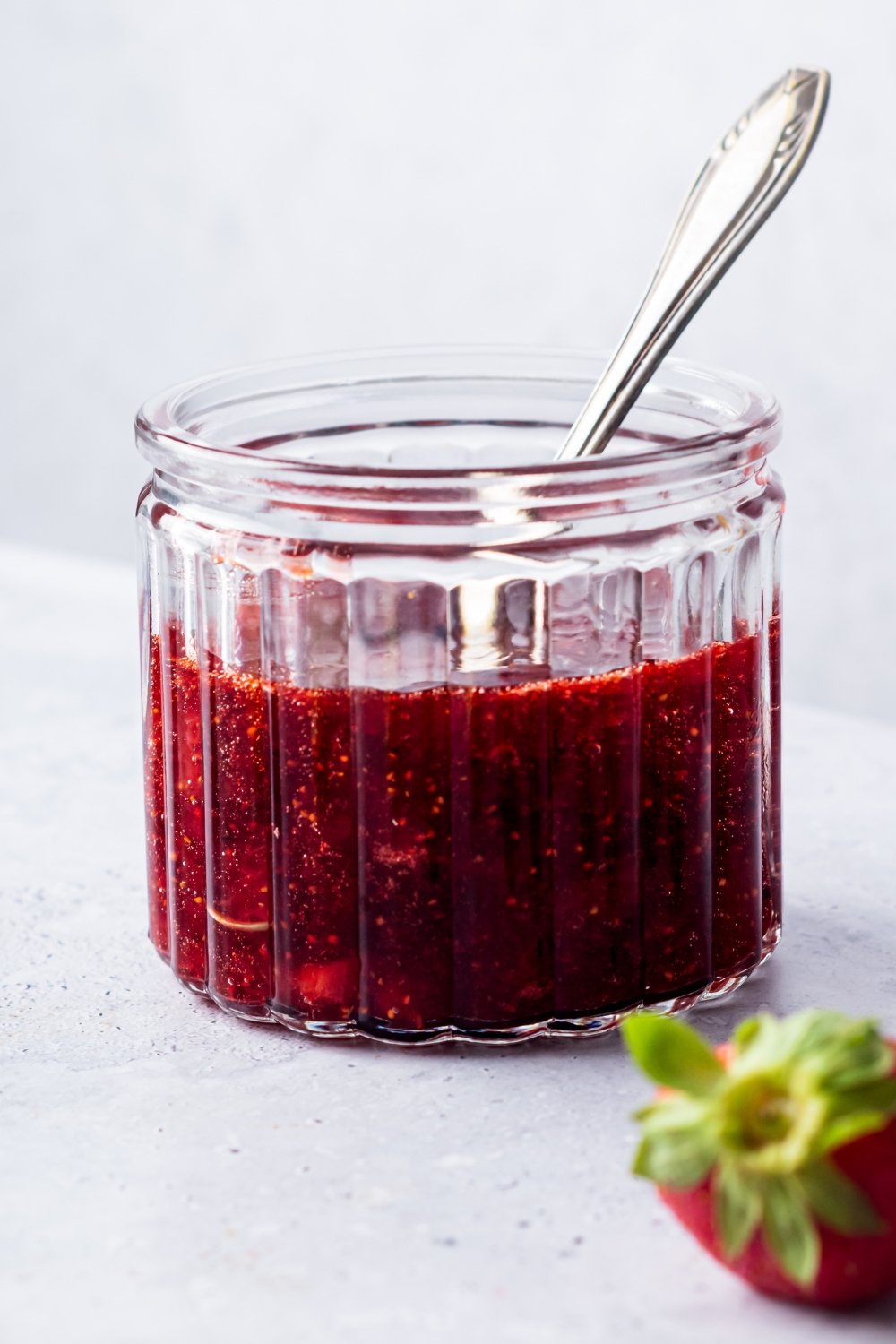 A glass jar filled with strawberry compote.