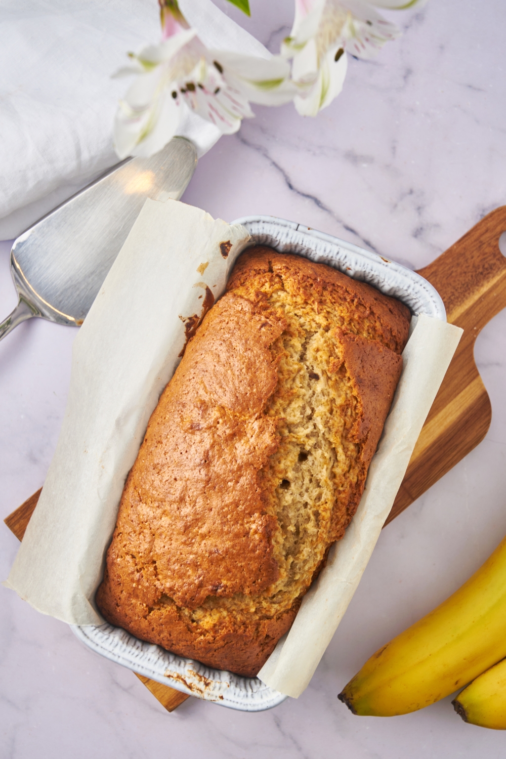 A loaf pan lined with parchment paper with baked banana bread.