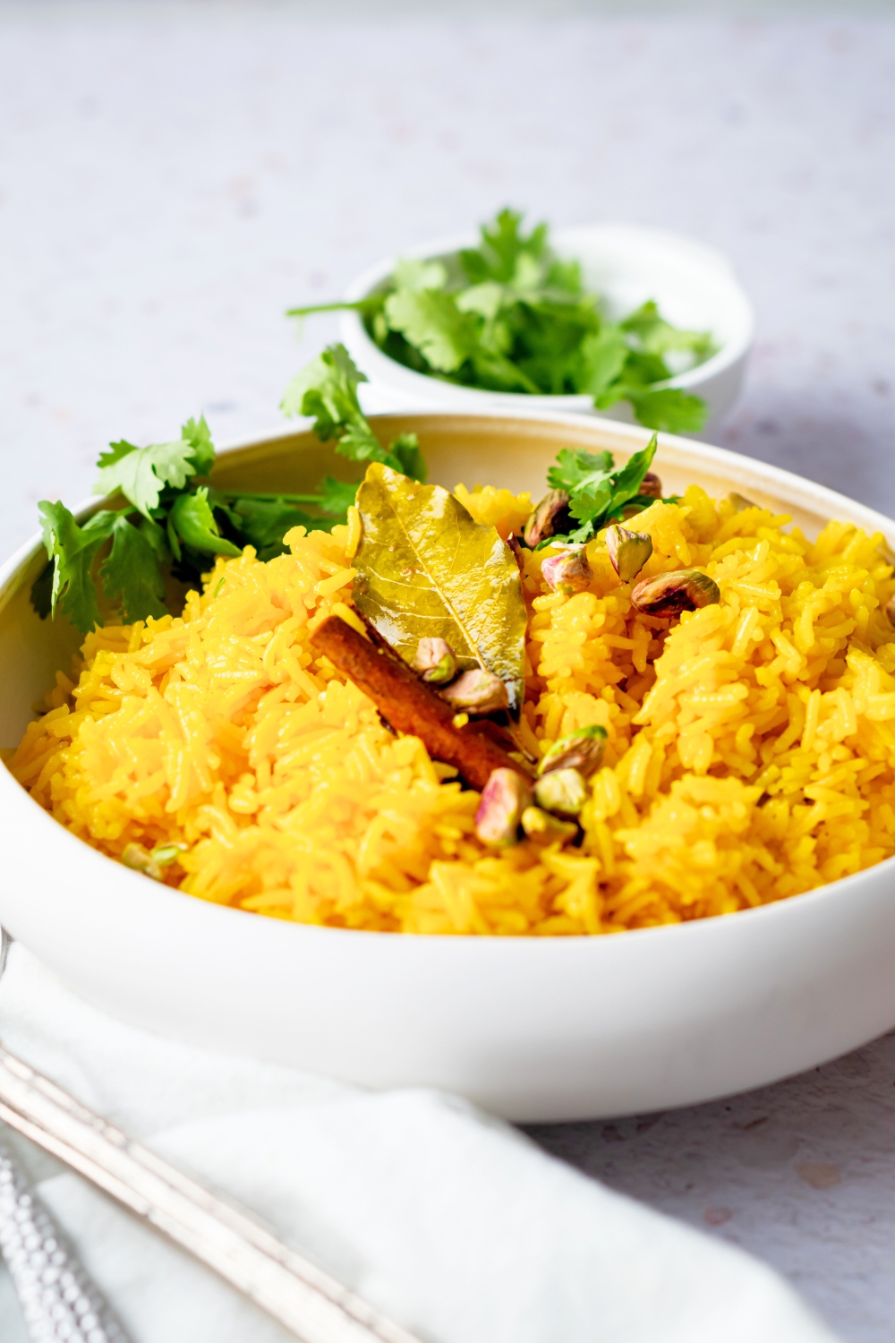 Part of a white bowl that is filled with turmeric rice.