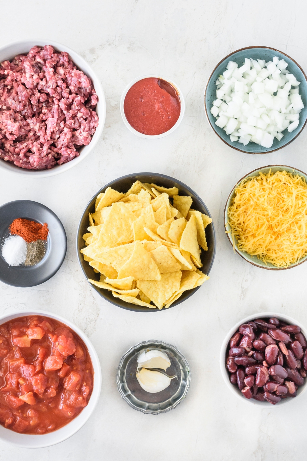 A countertop with multiple bowls with ingredients to make taco casserole.