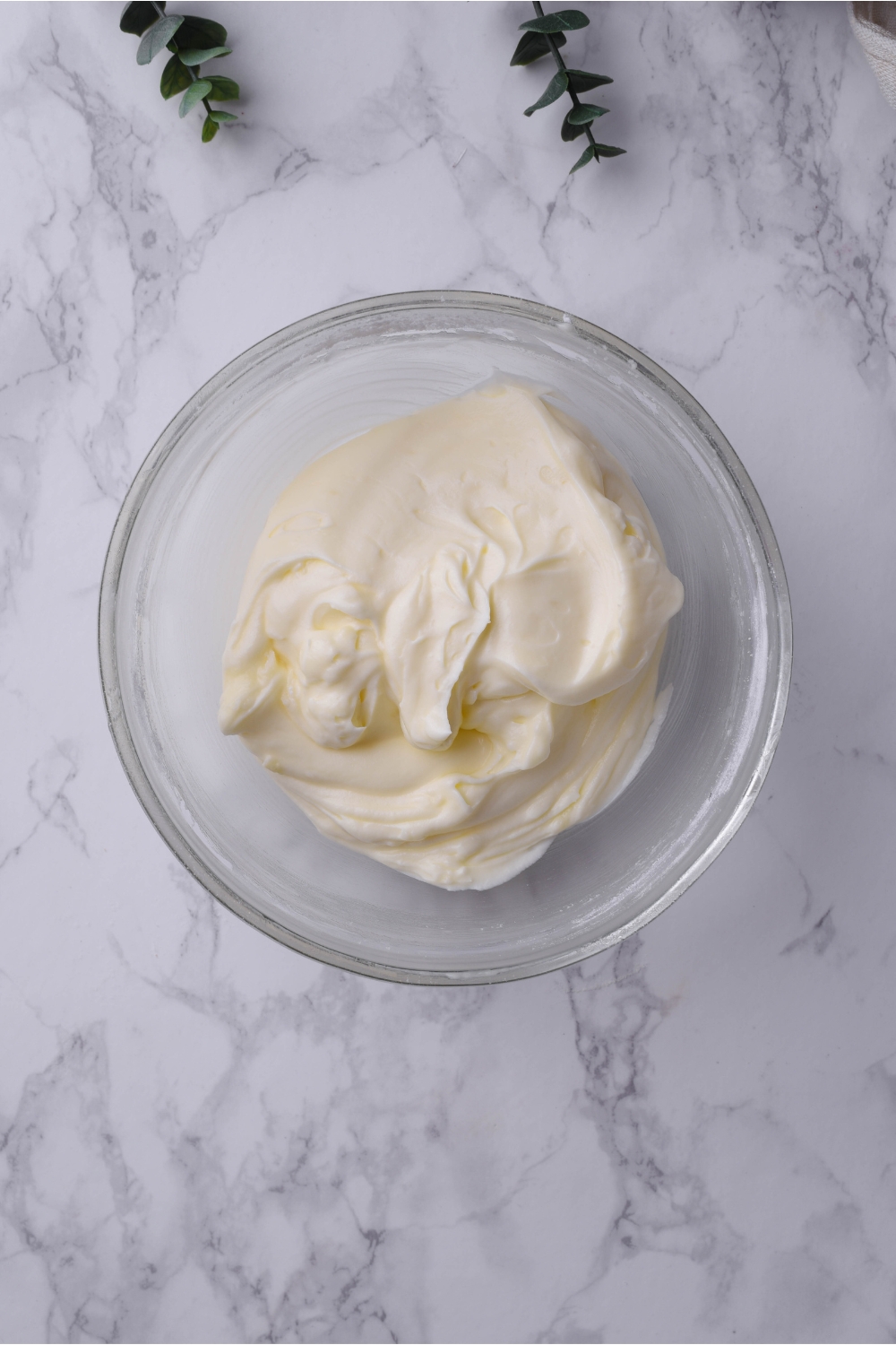 A clear bowl filled with cream cheese frosting.