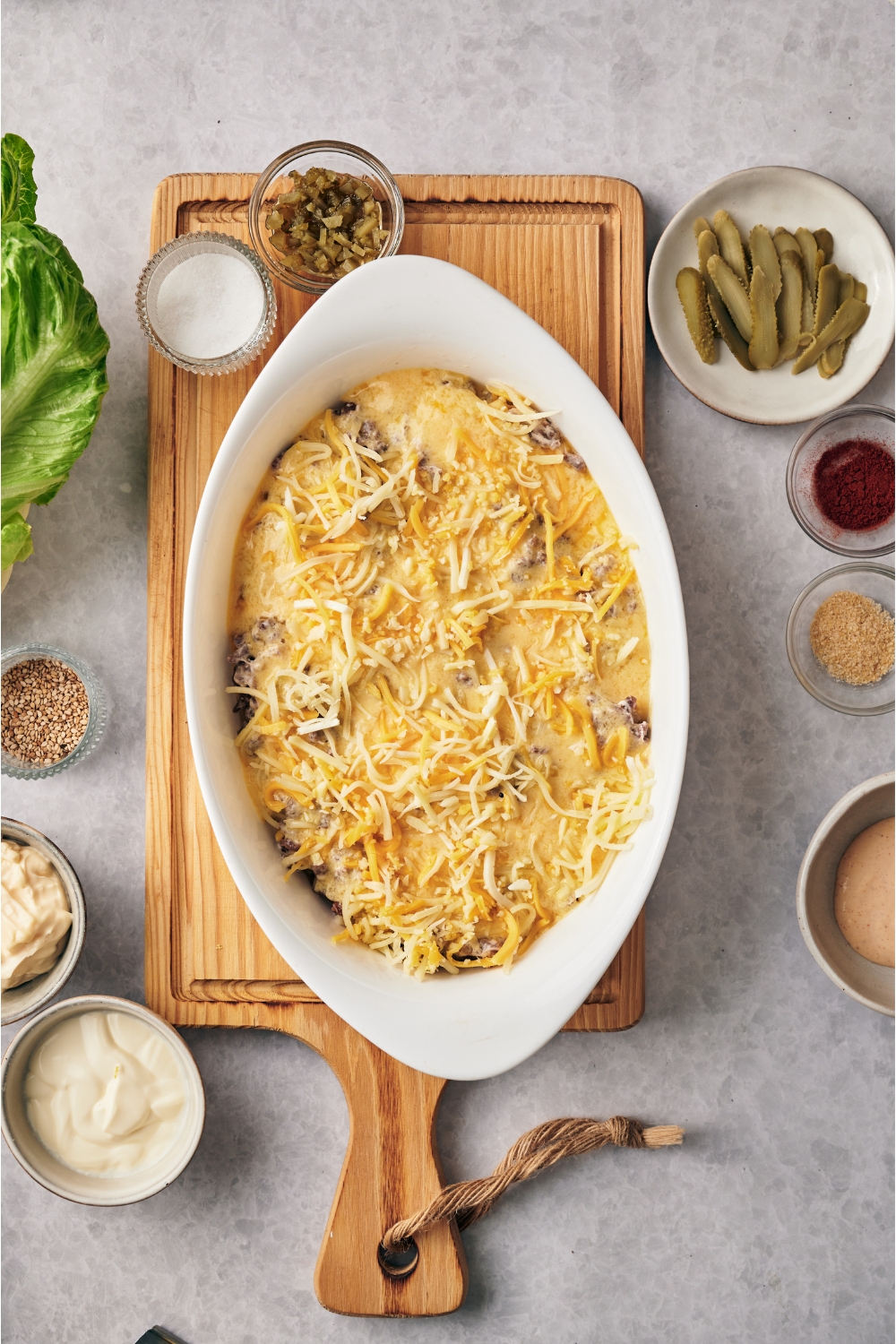White baking dish filled with cooked ground beef, a creamy sauce poured over top, and a layer of shredded cheese.