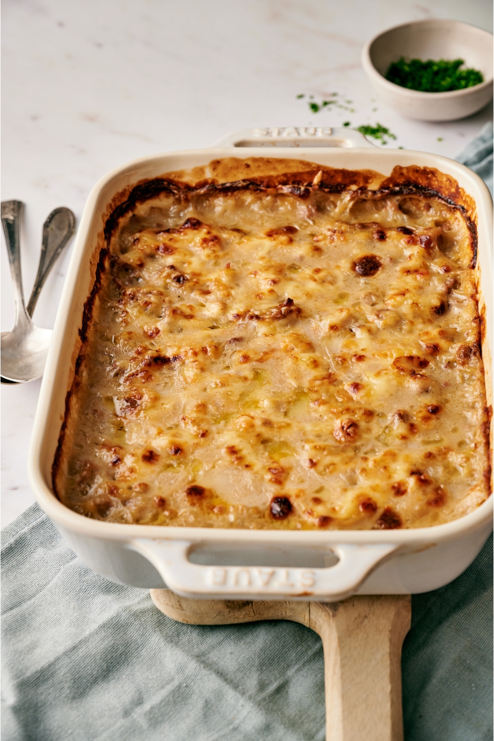 A white baking dish filled with freshly baked casserole covered in a layer of bubbly melted cheese.
