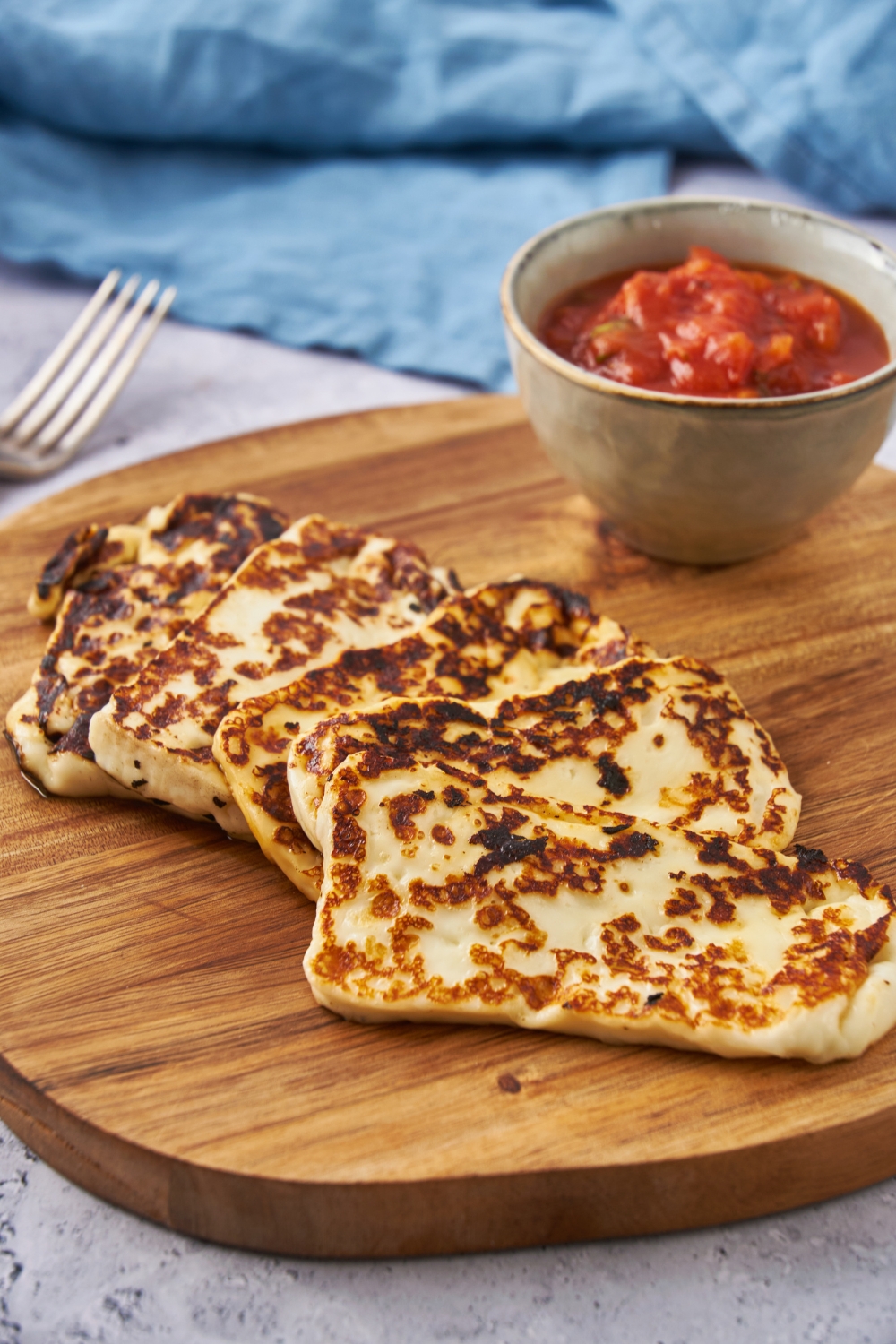 Finished fried cheese recipe on a cutting board with a side of salsa