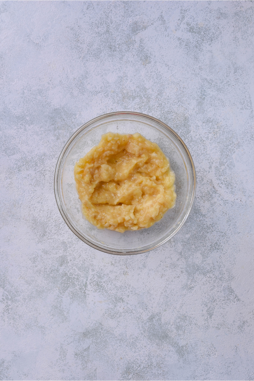 A clear bowl filled with mashed bananas.