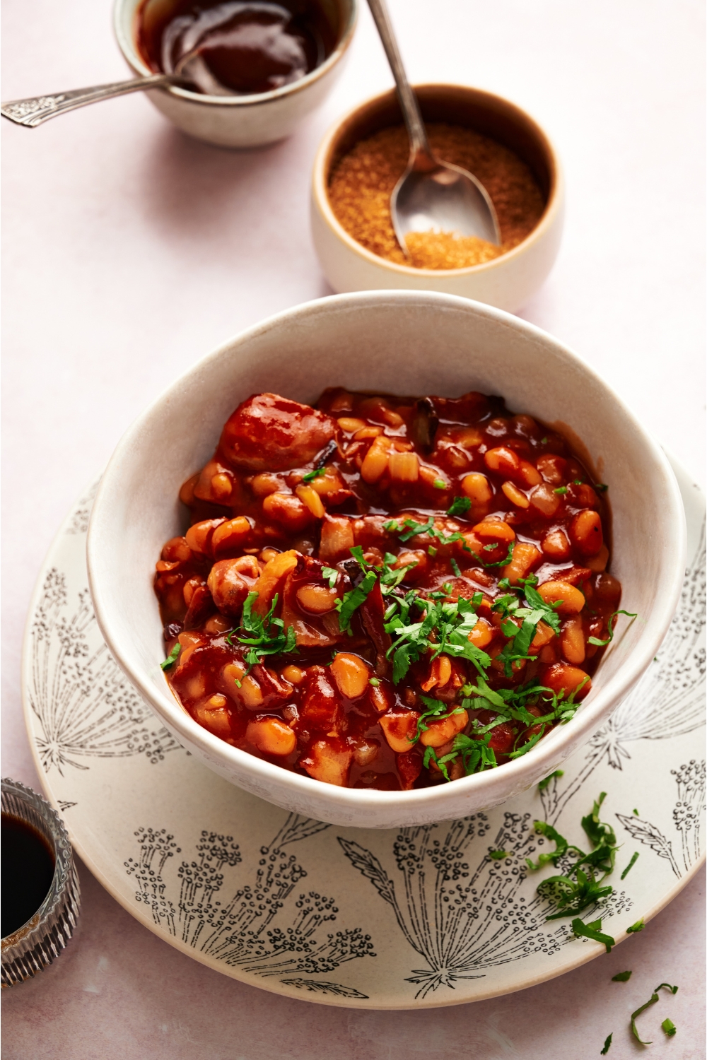 A bowl of baked beans in a brown sauce with fresh green herbs on top.