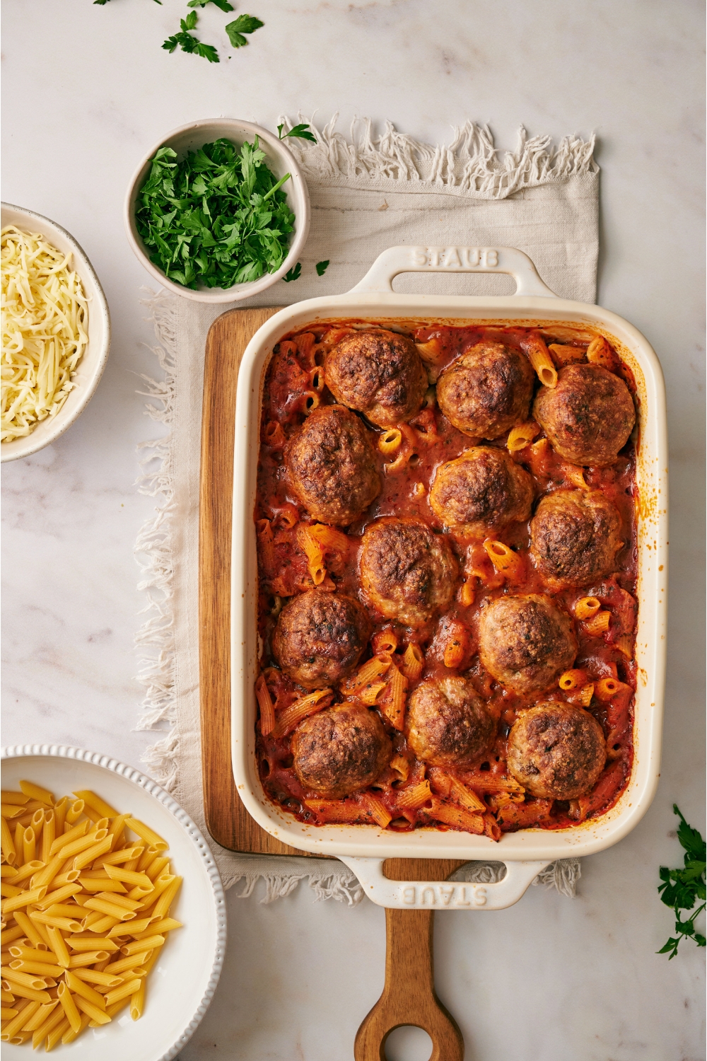 Freshly baked pasta with large browned meatballs on top.