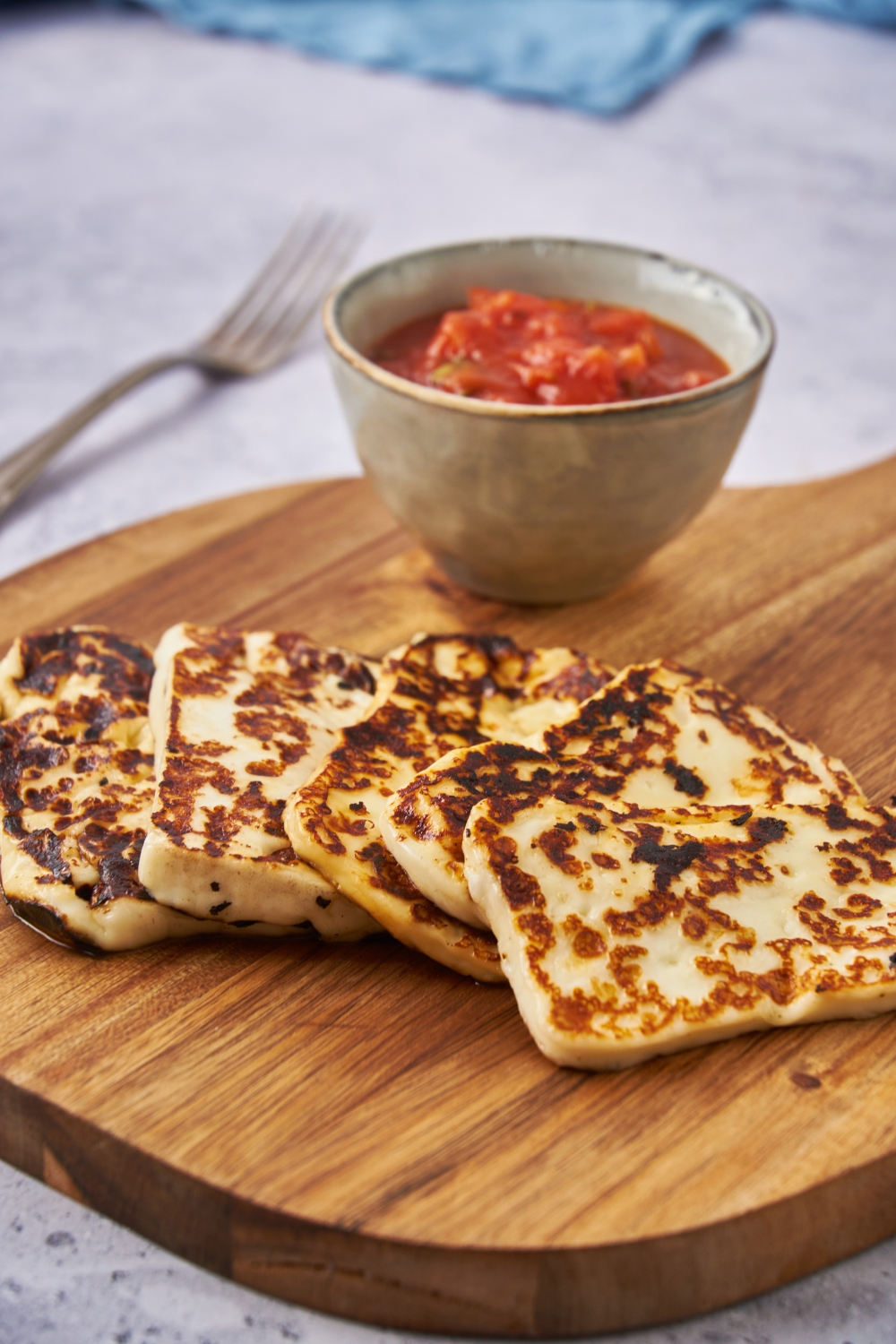 Finished fried cheese recipe on a cutting board with a side of salsa