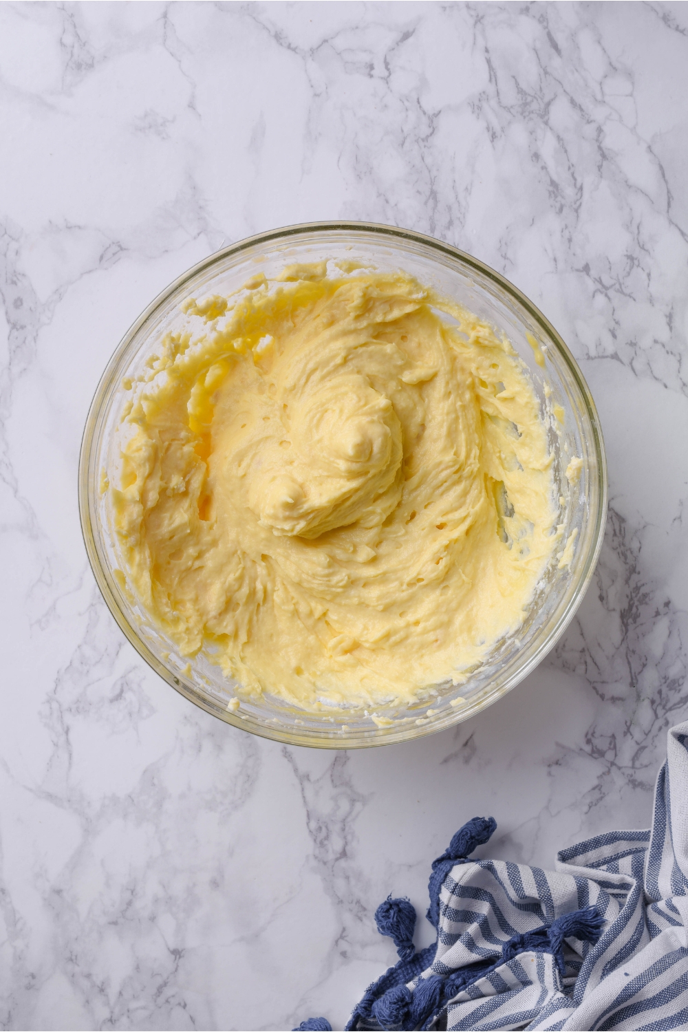 A clear bowl filled with yellow cheesecake batter.