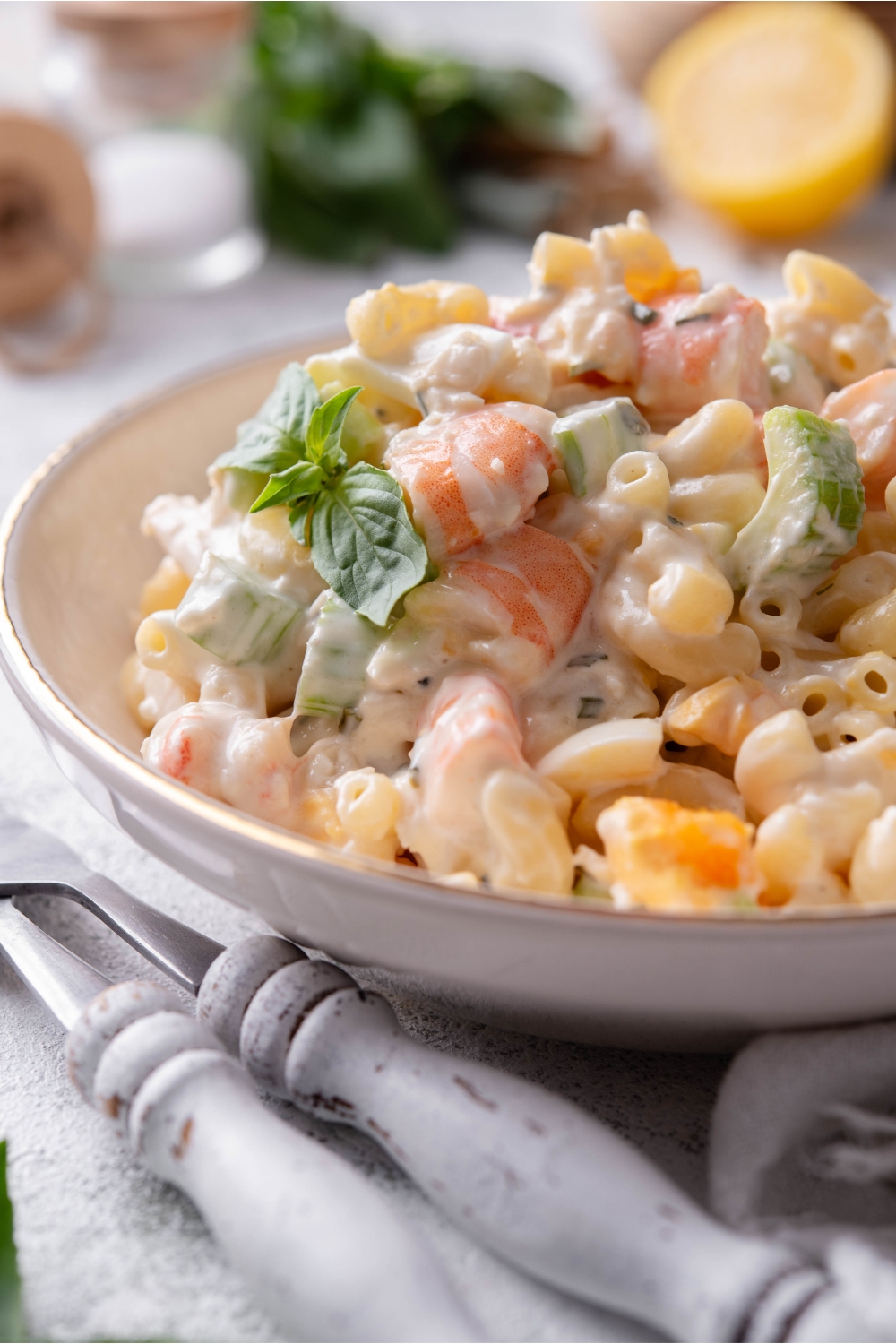 Close up of a bowl of seafood pasta salad with macaroni noodles and large chunks of shrimp and celery.