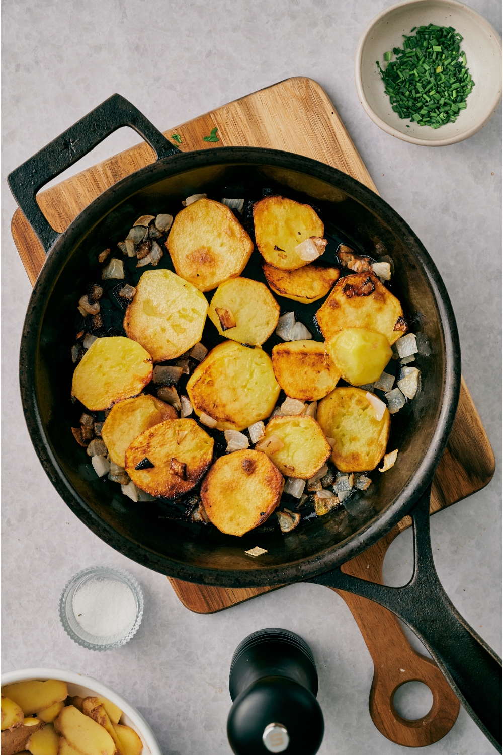 A skillet with pan-fried potatoes and sautéed diced onions in it.