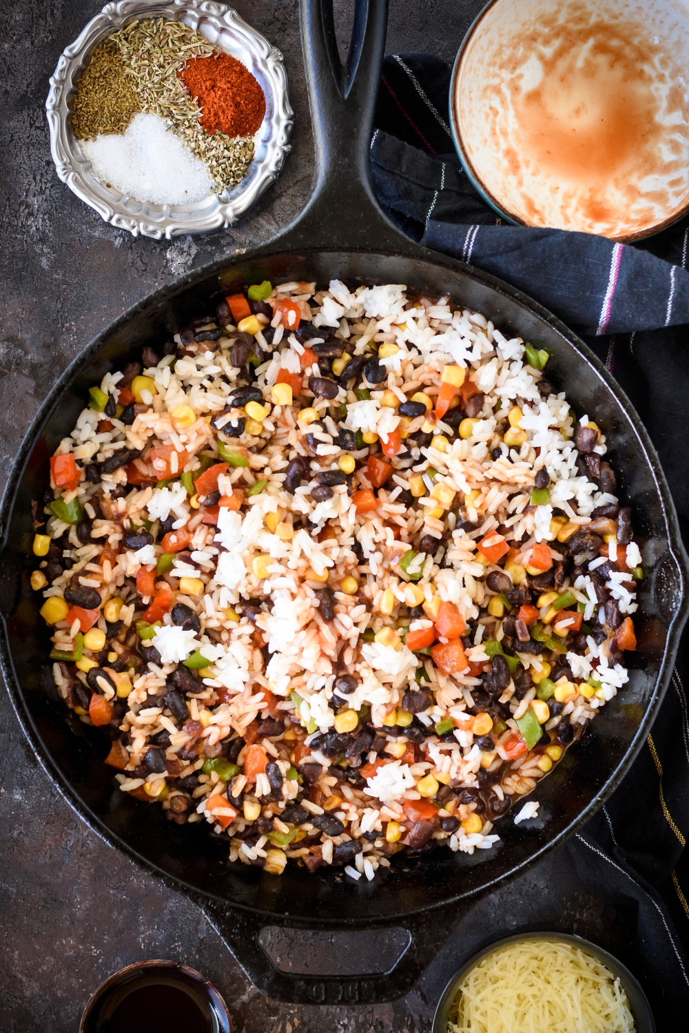 A skillet filled with white rice, black beans, corn, red peppers, and green peppers.