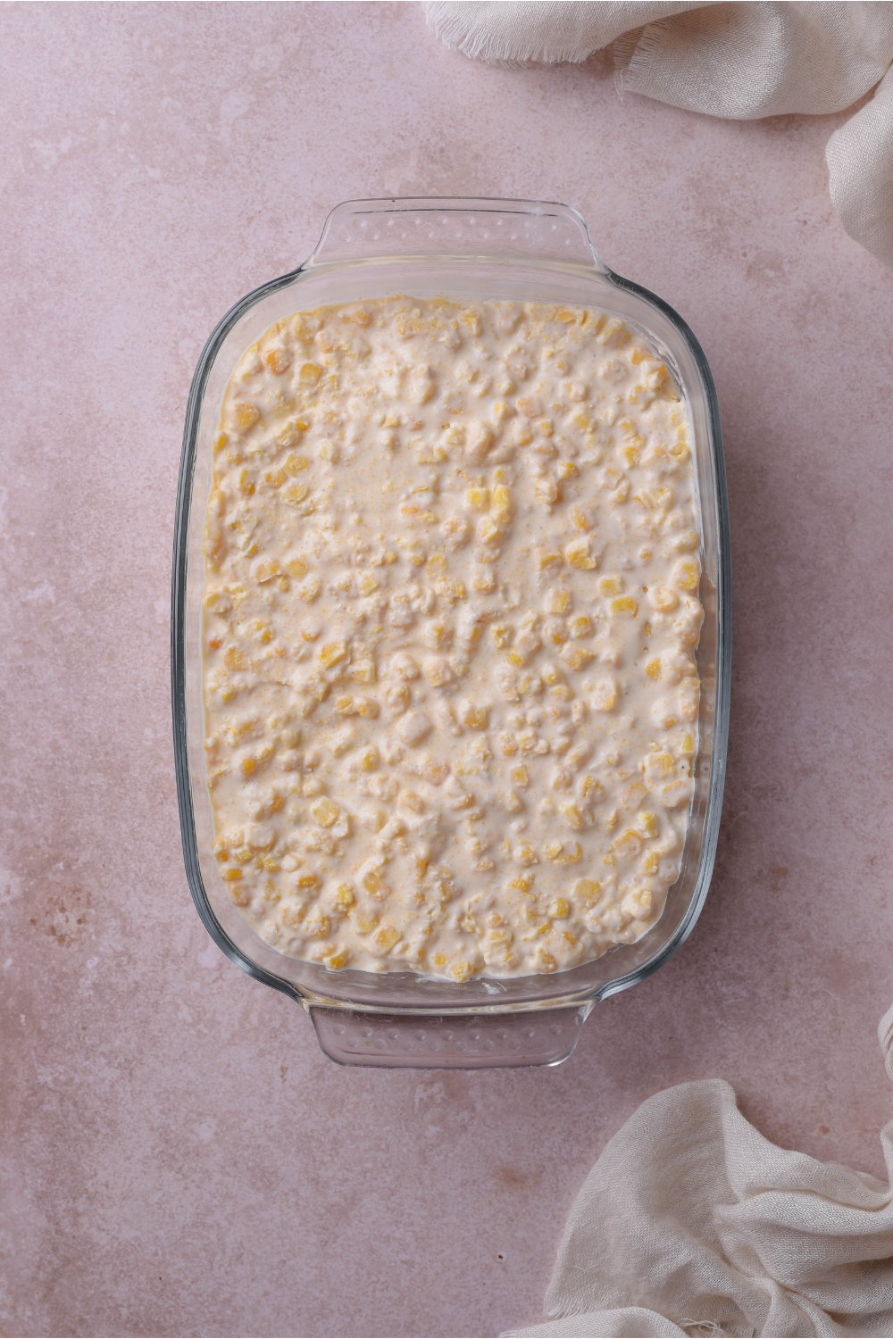 A baking dish filled with unbaked creamed corn casserole.