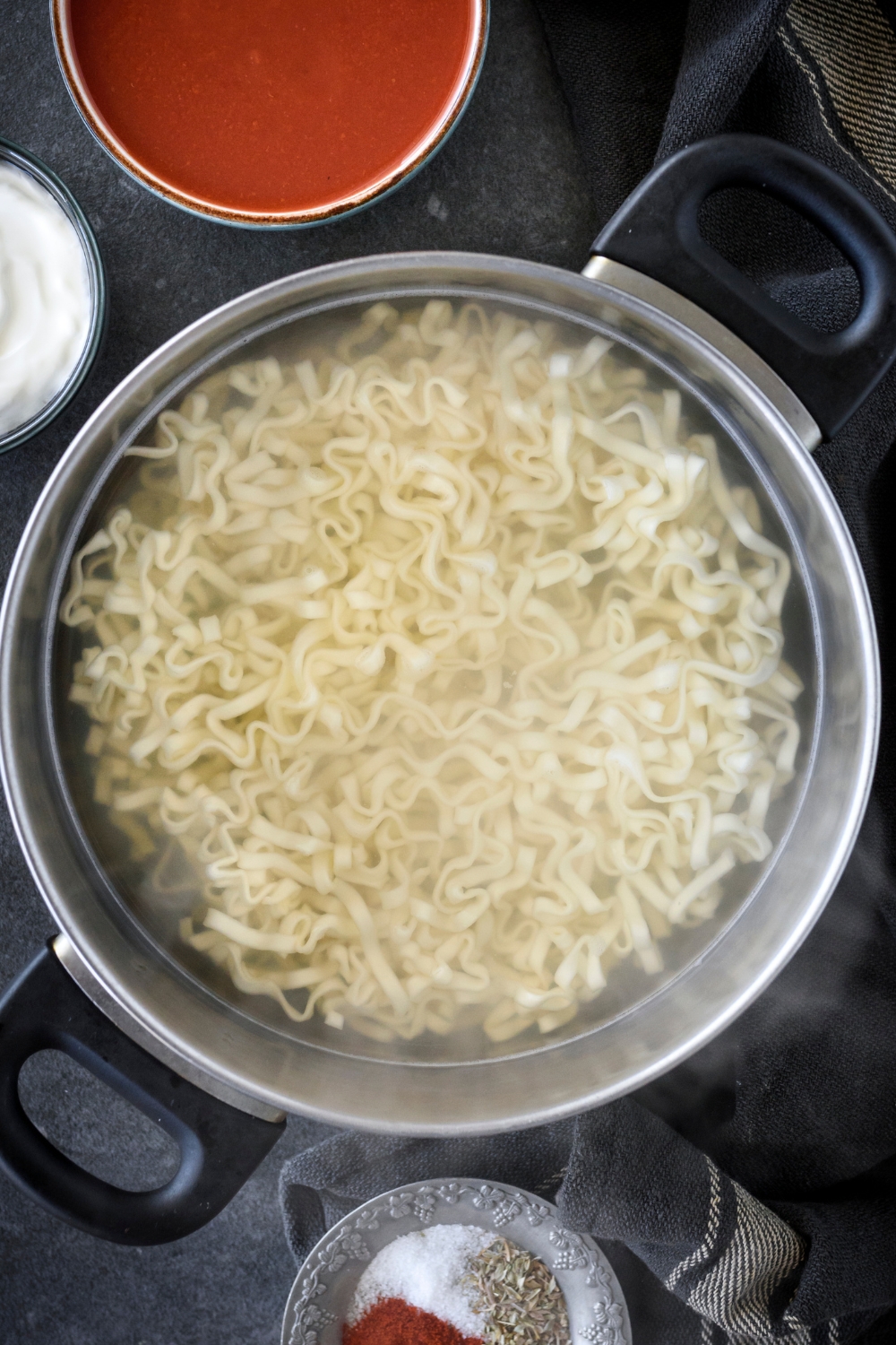 A large pot of water with noodles cooking in it.