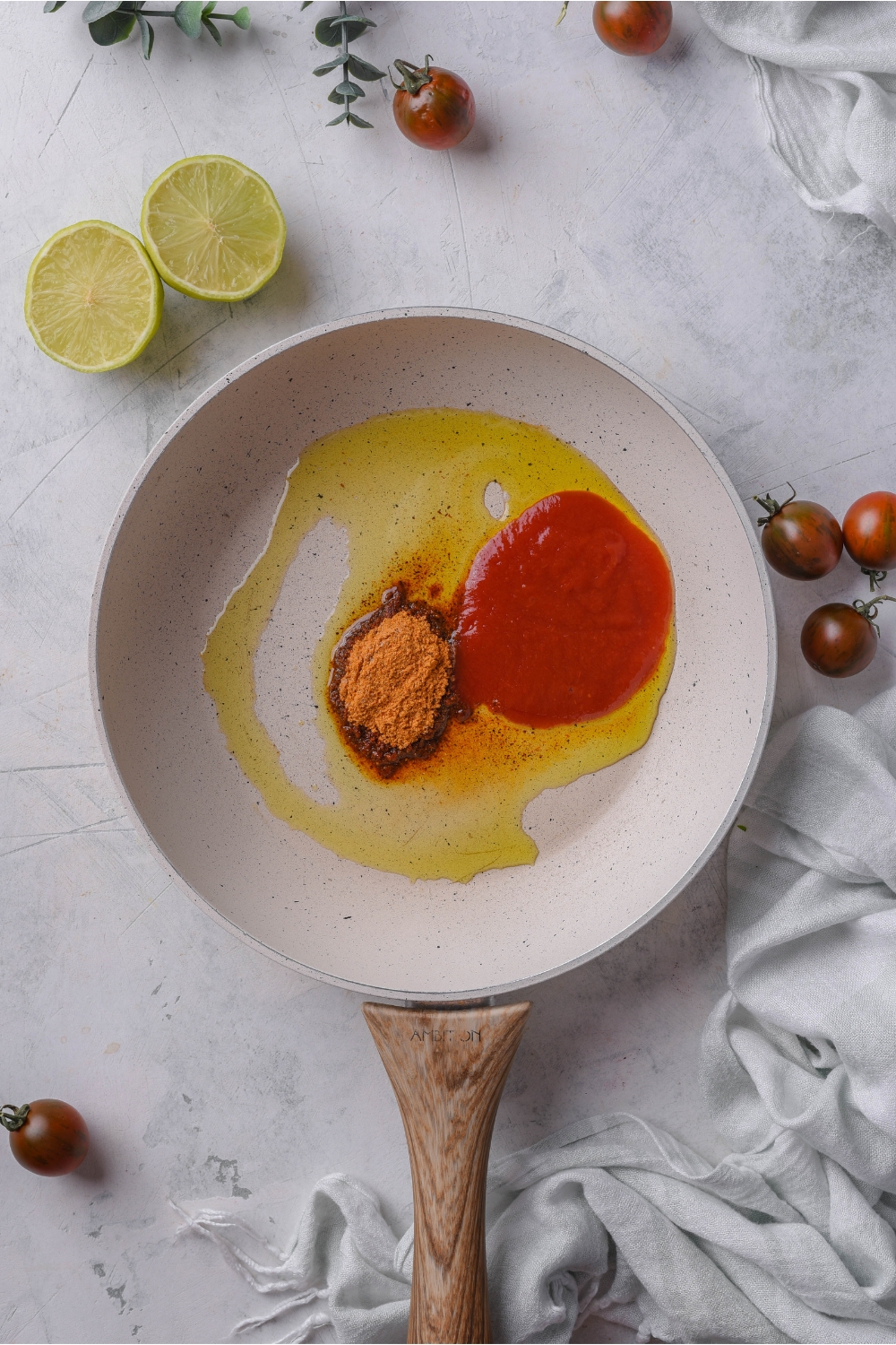 A skillet with oil, tomato paste, and seasoning added but not yet combined.