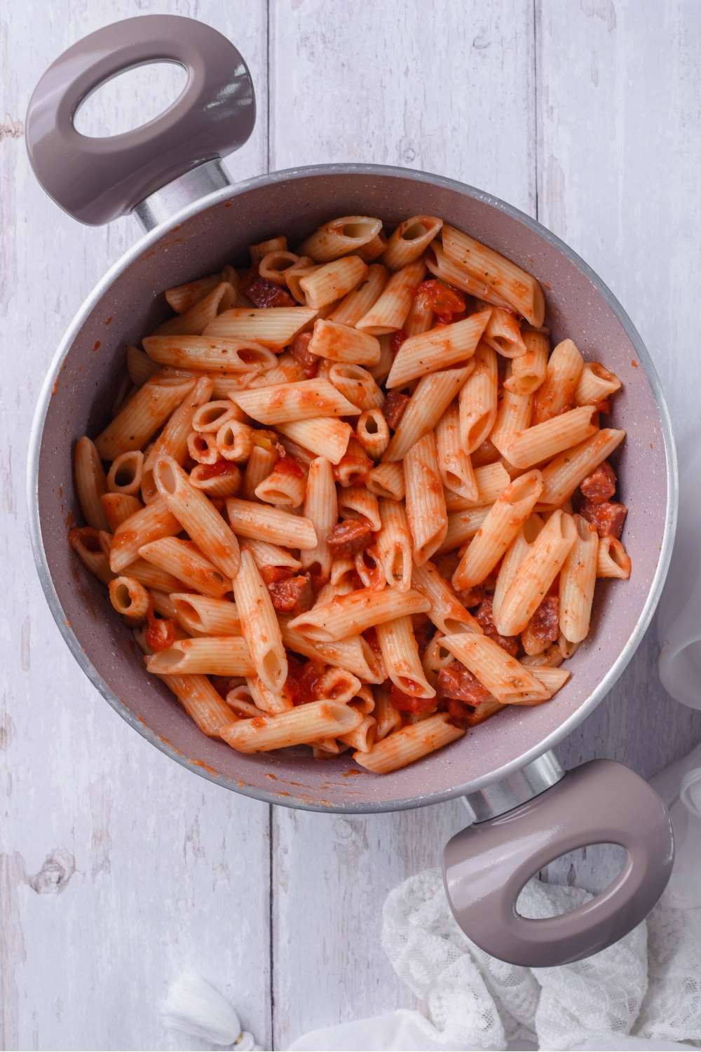 A grey pot filled with penne pasta in red sauce with tomato chunks and diced pepperoni.