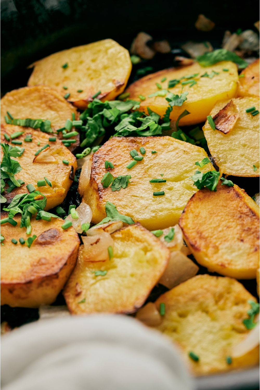 Pan fried potatoes and onions garnished with fresh green herbs.