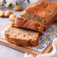 A loaf of cake mix banana bread that has two slices of the bread cut in front of it leaning against one another.