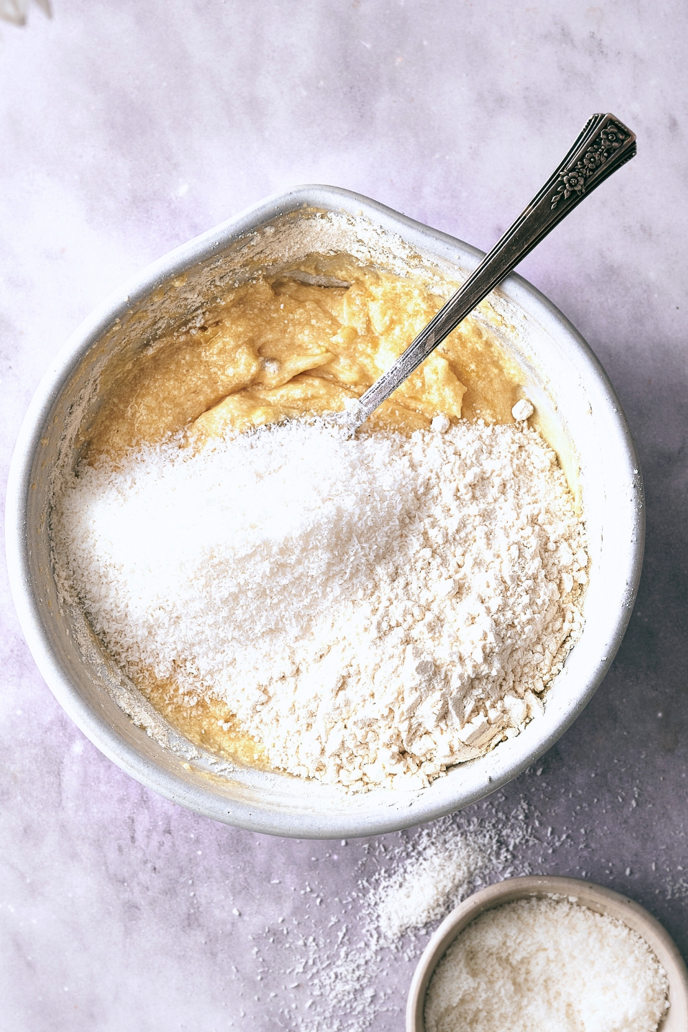 A mixing bowl with dry ingredients being added to the wet ingredients.