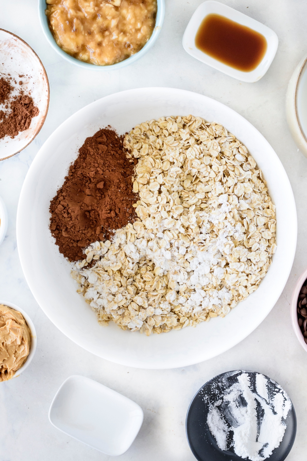 A mixing bowl with oats, cocoa powder, and baking powder.