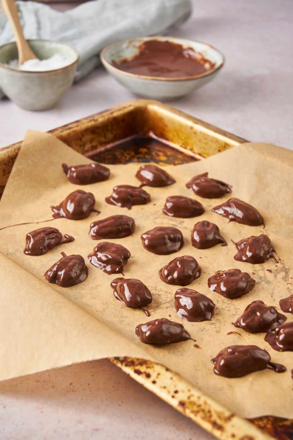 A baking sheet lined with parchment paper with chocolate covered pecans