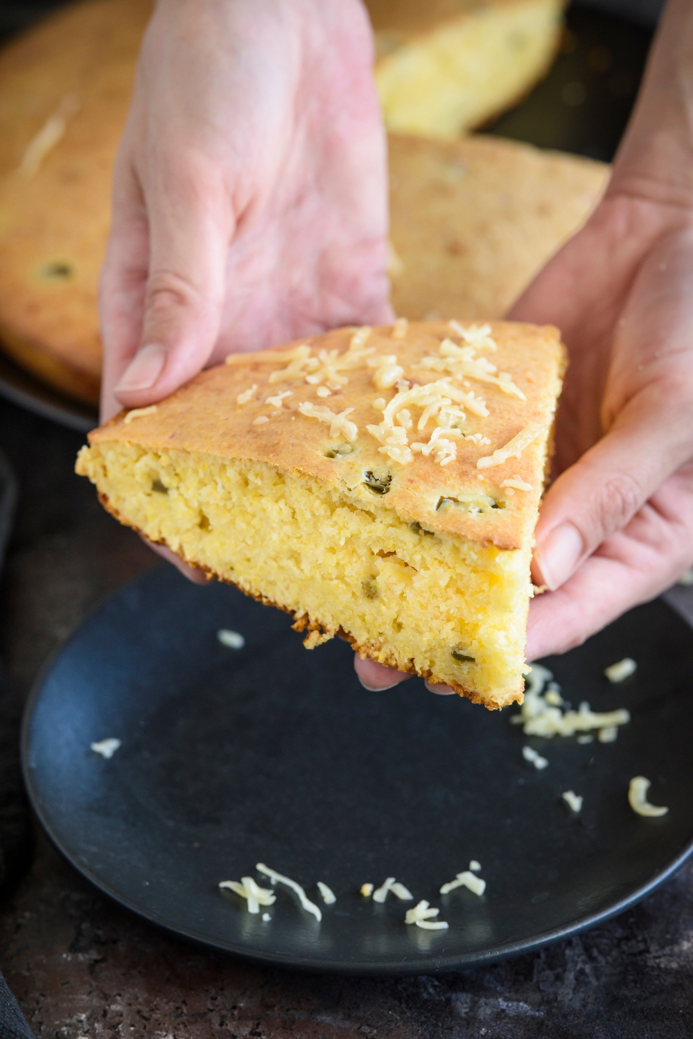 Two hands holding a slice of Jiffy jalapeno cornbread.