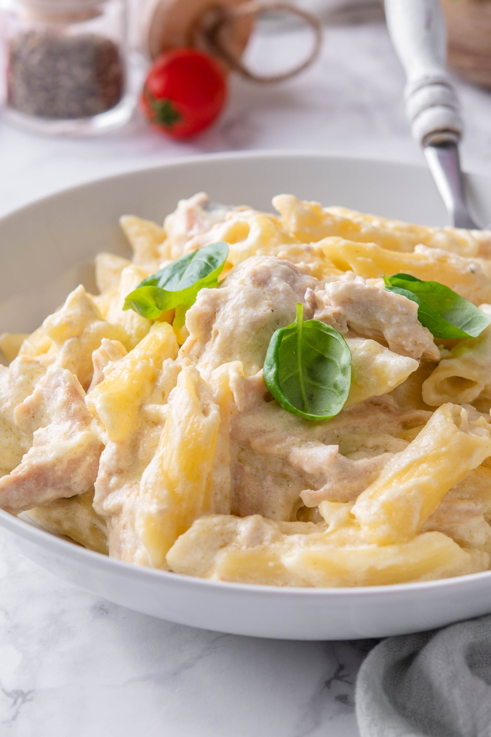 Chicken alfredo in part of a white bowl.