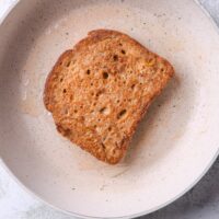 A slice of cinnamon french toast cooking in a skillet.