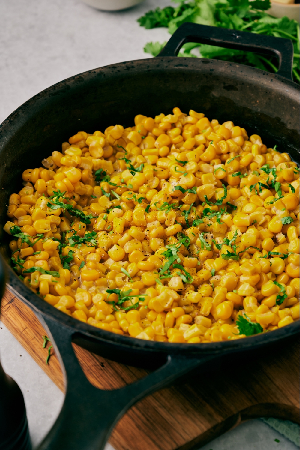 A cast iron skillet with fried corn topped with chopped cilantro.