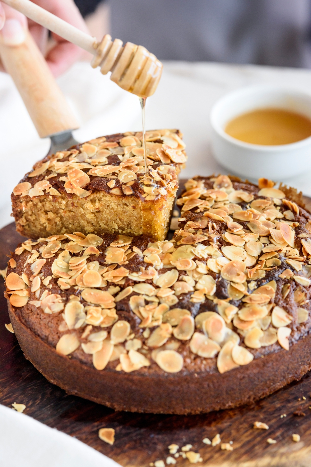 Close up of a honey cake with a thick slice being cut out.