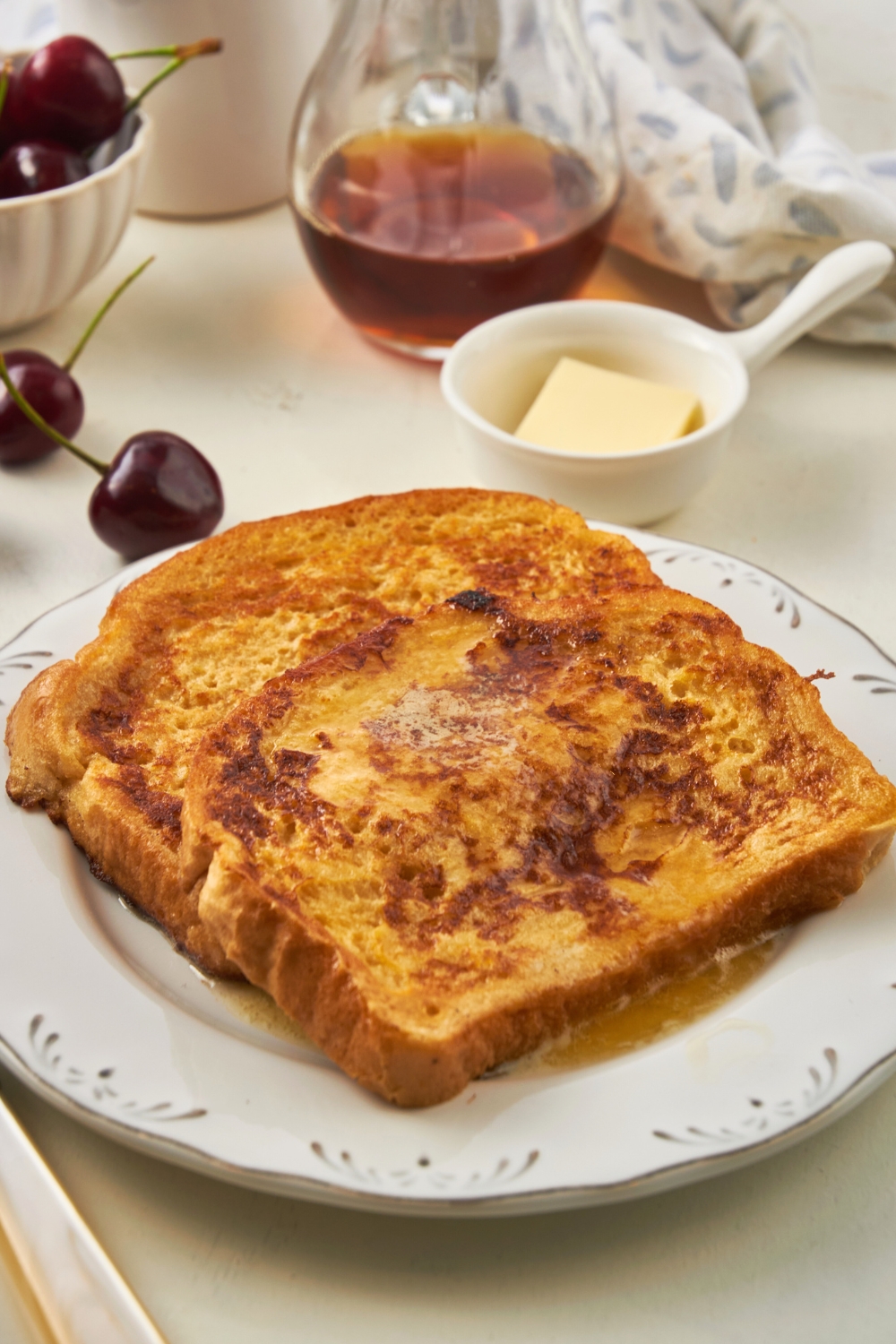 Two slices of french toast with syrup on them on a white plate.