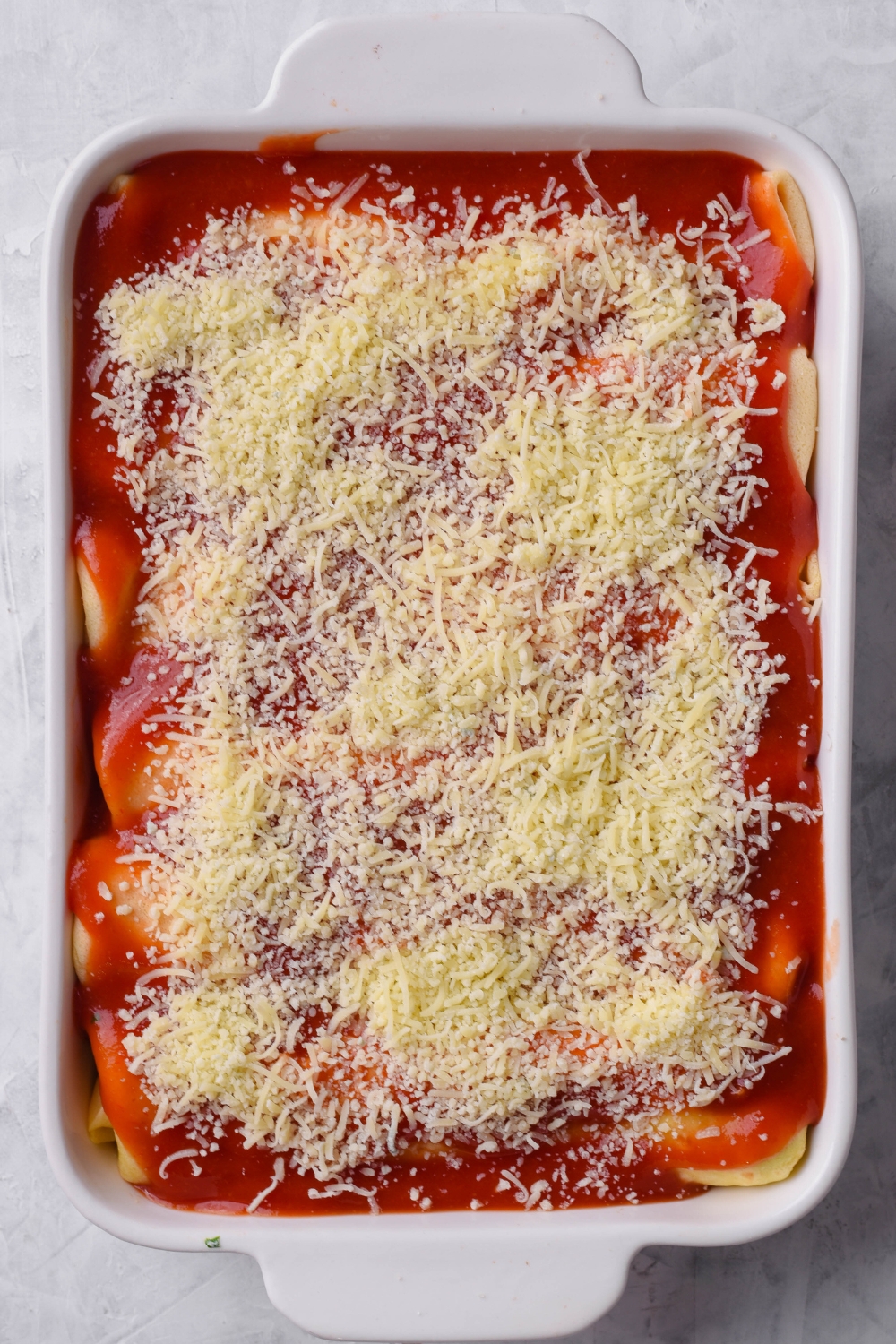 A baking dish with unbaked manicotti crepes.