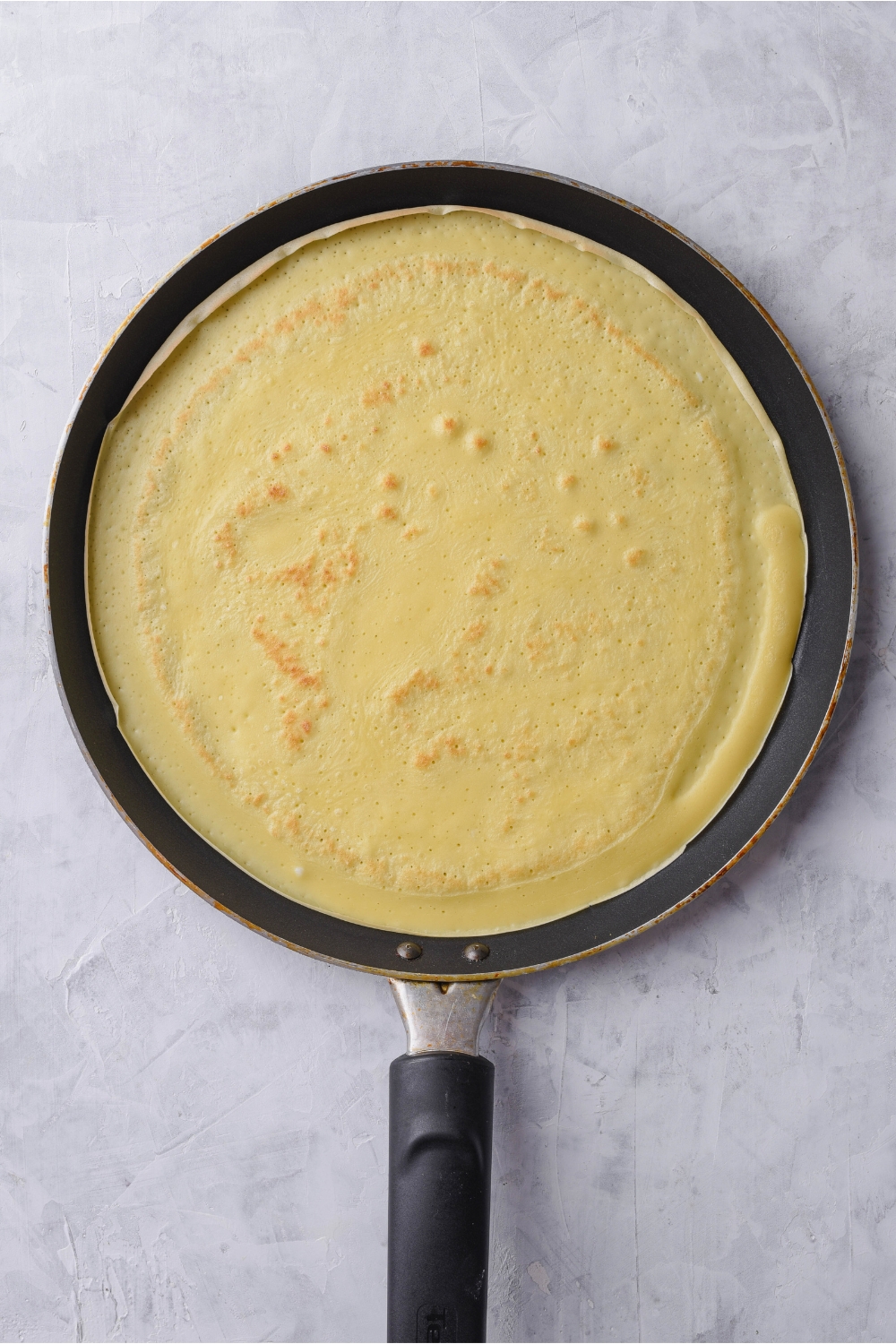 A crepe pan cooking a crepe.