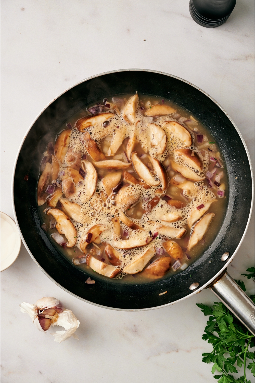 A skillet with the sauce and mushrooms being cooked down.