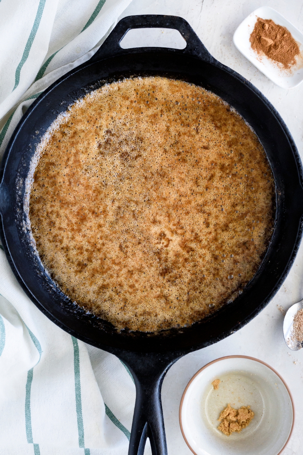 A cast iron skillet with melted butter, sugar, and spice sauce.