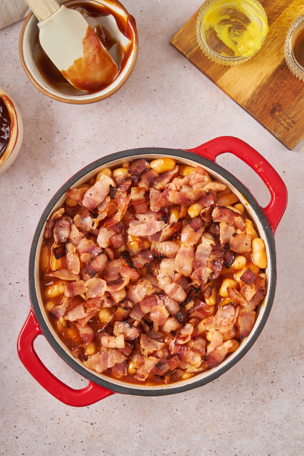 Cooked bacon on top of baked beans in a round baking dish.
