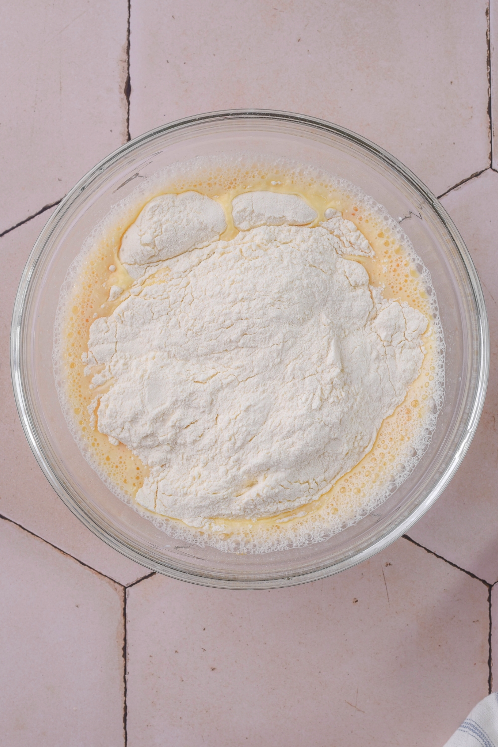 A mixing bowl with flour being added to the wet ingredients.