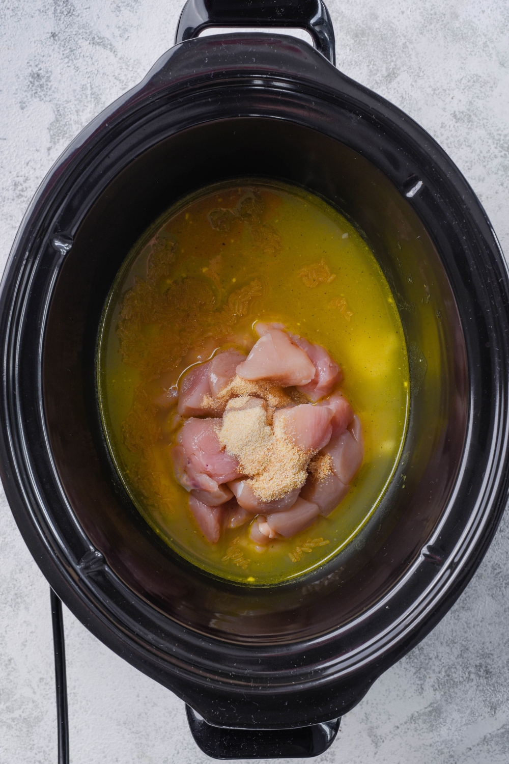 Chicken stock, seasonings, and chicken in a crock pot.