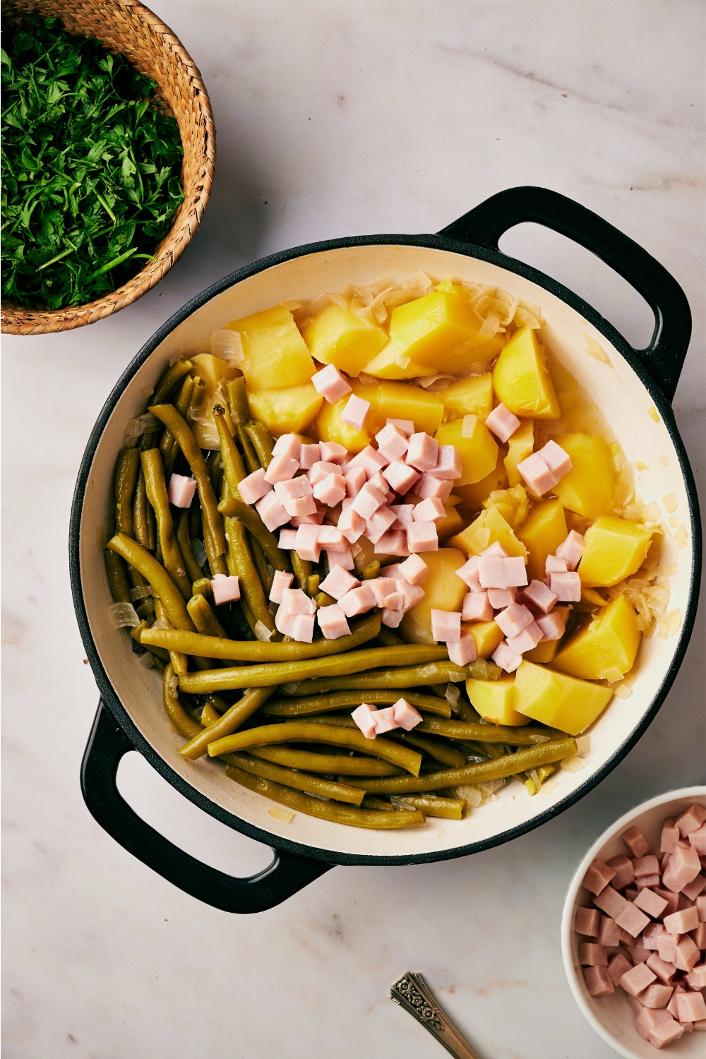 A pot with green beans, potatoes, and diced ham.