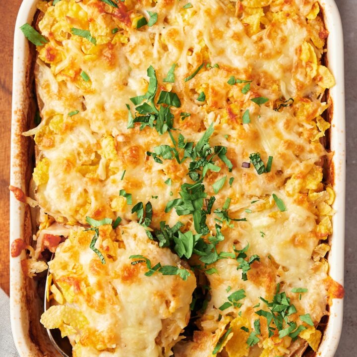 A casserole dish on a wooden serving board with baked shipwreck casserole.