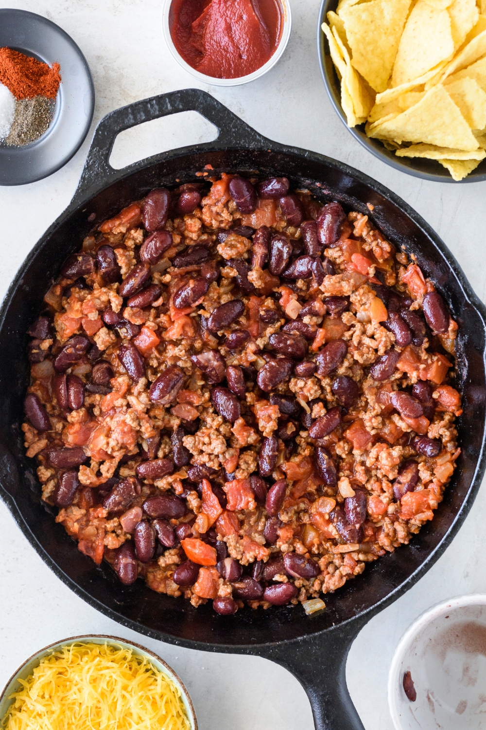 A large frying pan with the ground beef, bean, and tomato mixture cooking.