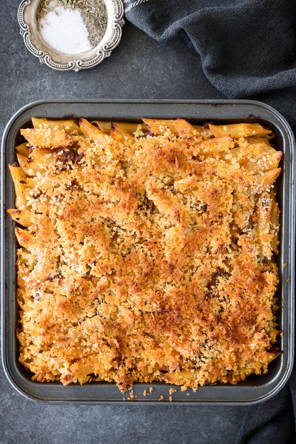 A square baking dish filled with freshly baked Italian casserole covered in golden brown bread crumbs.