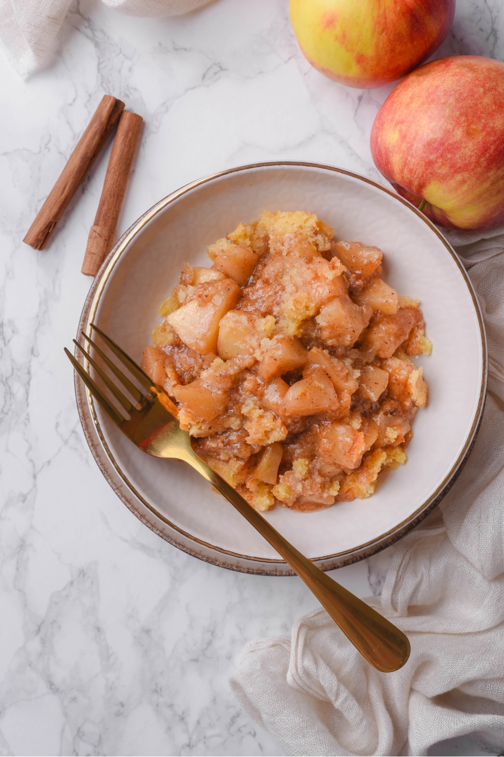 Overhead view of a bowl filled with caramel apple dump cake. There is a fork in the bowl.