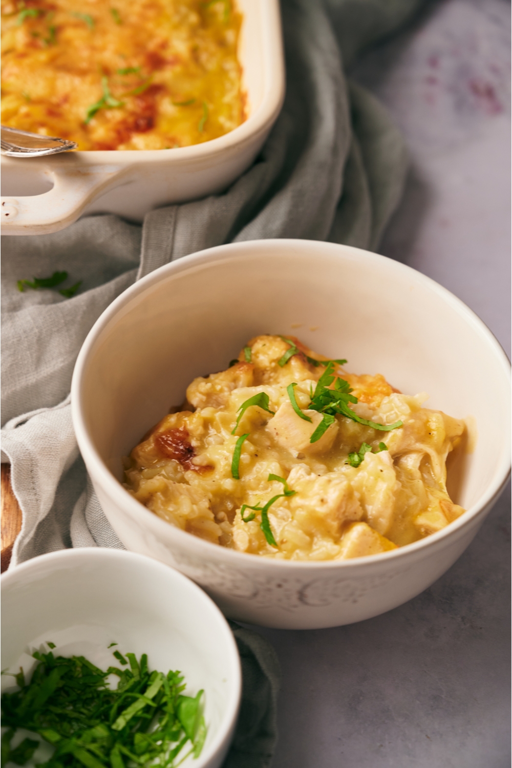 A bowl filled with chicken and rice casserole in a creamy soup mixture and garnished with fresh green herbs.